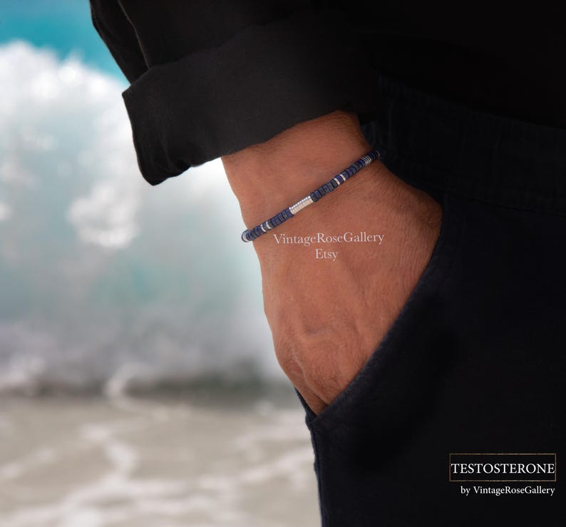 Puede incluir: Una pulsera de cuentas con cuentas azul marino y plateadas alternas. La pulsera se lleva en la mu&ntilde;eca, con un fondo oscuro. Un accesorio sencillo y elegante.