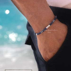 Puede incluir: Una pulsera de cuentas azul marino con detalles plateados se lleva en la mu&ntilde;eca. La pulsera est&aacute; hecha de peque&ntilde;as cuentas redondas. El texto "TESTOSTERONE" se muestra en un recuadro, con "by Vintage Rose Gallery" debajo.