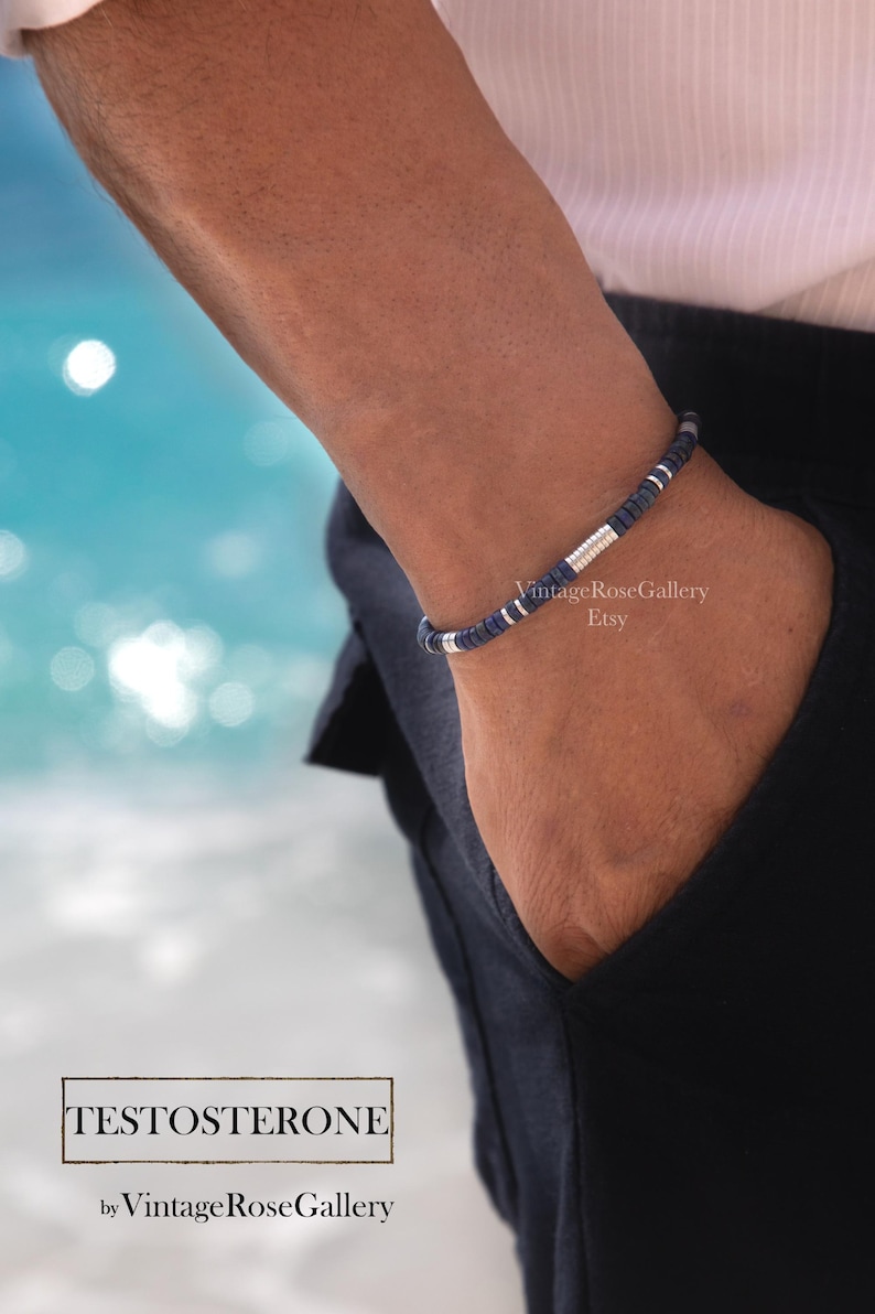 Puede incluir: Una pulsera de cuentas azul marino con detalles plateados se lleva en la mu&ntilde;eca. La pulsera est&aacute; hecha de peque&ntilde;as cuentas redondas. El texto "TESTOSTERONE" se muestra en un recuadro, con "by Vintage Rose Gallery" debajo.
