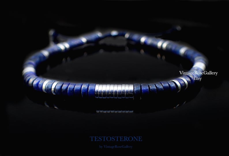 Puede incluir: Una pulsera de cuentas azul oscuro con detalles plateados. La pulsera presenta una serie de cuentas circulares azul oscuro intercaladas con anillos de metal plateado. La palabra "TESTOSTERONE" est&aacute; impresa en la parte inferior de la imagen.