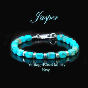 May include: A bracelet featuring bright turquoise blue, cube-shaped jasper beads interspersed with small, smooth silver-toned metal spacers. The piece includes a silver-toned lobster claw clasp. The text Jasper, VintageRoseGallery, and Etsy appear.