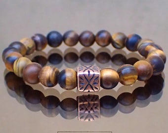 May include: A brown and gold tiger's eye beaded bracelet with a copper charm featuring a geometric design. The bracelet is called "TESTOSTERONE" by VintageRoseGallery.