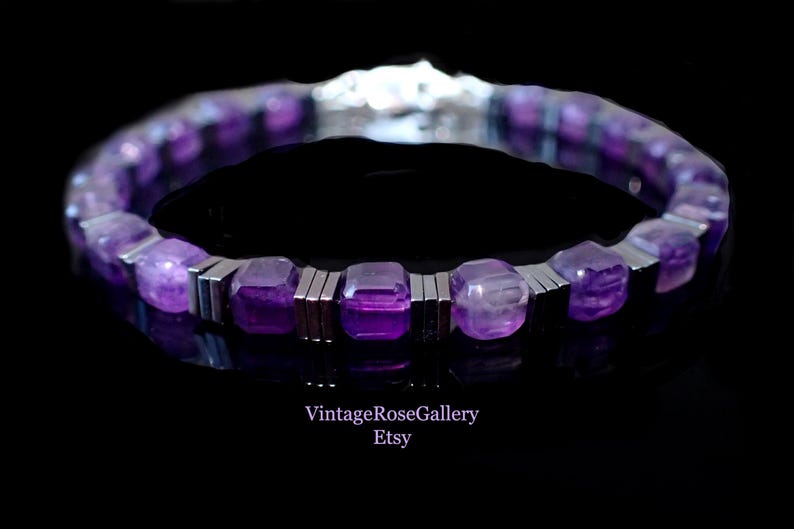 May include: A bracelet featuring purple gemstones and silver-coloured metal. The amethyst stones are square-cut. The bracelet is set against a black background. The Etsy shop name "VintageRoseGallery" is visible.