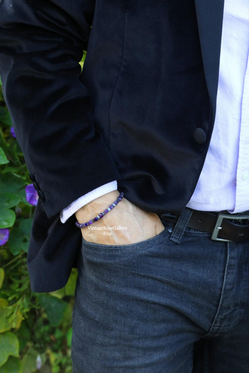 May include: A bracelet with purple and silver beads is worn on a wrist. The person is wearing a black blazer, a white collared shirt, and dark blue jeans. The Etsy shop name "VintageRoseGallery" is visible.
