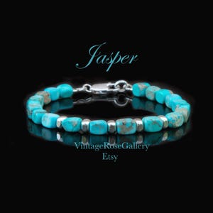 May include: A bracelet featuring turquoise-colored, rectangular jasper beads interspersed with small, polished silver-toned metal spacer beads. The piece includes a silver-toned lobster claw clasp. The text Jasper, VintageRoseGallery, and Etsy appear.