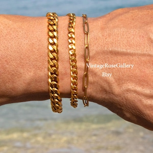 Peut inclure: Trois bracelets dorés de styles différents sont présentés. On distingue une chaîne gourmette épaisse, une chaîne gourmette plus fine et une chaîne à maillons délicate. L'arrière-plan est une mer floue.