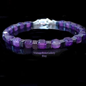 May include: A bracelet with purple gemstones and silver-coloured metal. The bracelet is shown against a dark background, emphasising its reflective properties. The Etsy shop name "VintageRoseGallery" is visible.