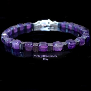May include: A purple beaded bracelet with silver accents. The bracelet has faceted purple beads and rectangular silver metal spacers. The bracelet is displayed on a black surface. The Etsy shop name "VintageRoseGallery" is visible.