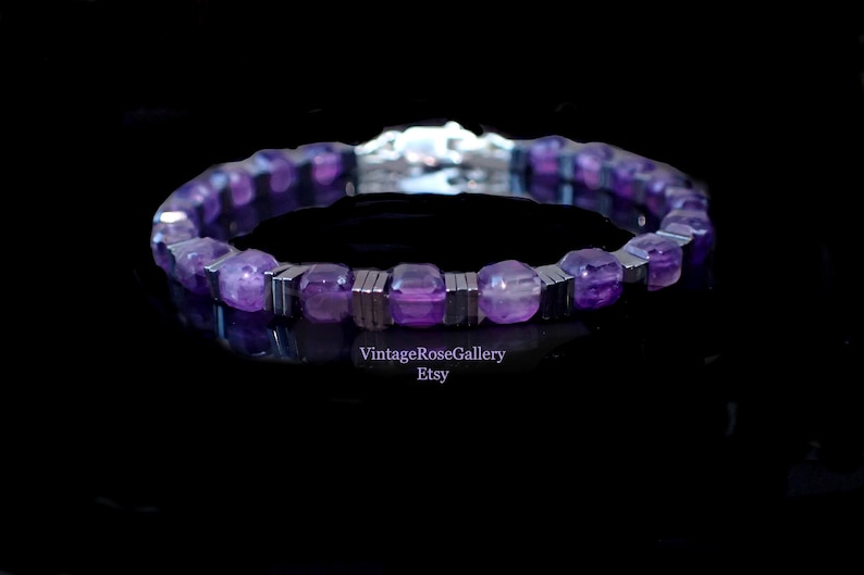 May include: A purple beaded bracelet with silver accents. The bracelet has faceted purple beads and rectangular silver metal spacers. The bracelet is displayed on a black surface. The Etsy shop name "VintageRoseGallery" is visible.