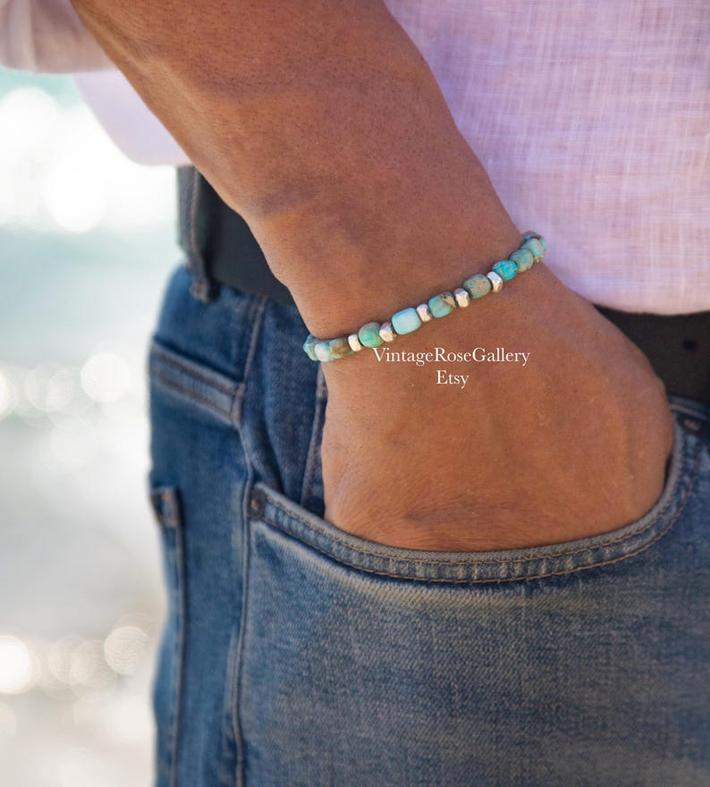 May include: A beaded bracelet featuring alternating turquoise-colored stone beads and small metallic silver-toned spacers. The bracelet is worn on a wrist and includes the text VintageRoseGallery Etsy printed in white on the image surface.