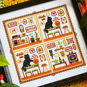 Puede incluir: Bordado de punto de cruz con un gato negro sentado en una mesa en una habitación con una chimenea, un tocadiscos y otros muebles. El texto "Life's a Bitch and So Am I" está bordado en la tela.