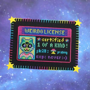 Op de afbeelding: Een kruissteek "Weirdo License" met een cartoon alien karakter. De zwarte achtergrond is omlijst met kleurrijke steken en gele steraccenten. De licentietekst bevat "gecertificeerd", "1 of a kind" en "probing" als vaardigheid.