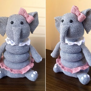 May include: A gray crocheted elephant toy wearing a pink tutu and a pink bow. The elephant has white accents on its feet and a white crocheted collar.