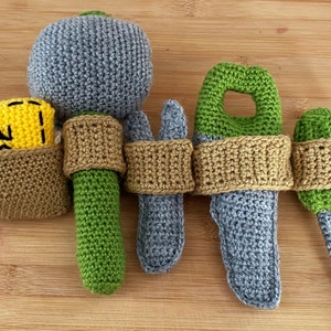 May include: A set of crocheted toy tools, including a hammer, wrench, pliers, and screwdriver. The tools are connected by a brown crocheted belt with a yellow crocheted pouch that says "#2" on it.