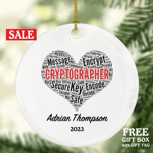 May include: White ceramic Christmas ornament with a red heart-shaped word cloud featuring the word "CRYPTOGRAPHER" and other related terms. The ornament is personalized with the name "Adrian Thompson" and the year "2023".
