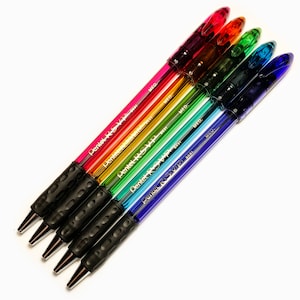 Könnte beinhalten: Ein Set mit sechs bunten, einziehbaren Kugelschreibern mit schwarzen Gummigriffen. Die Stifte sind mit "Pentel RSVP" und "MED" beschriftet.