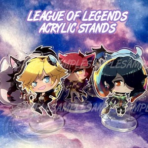 May include: Three League of Legends acrylic stands featuring chibi-style characters with vibrant hair and detailed outfits. The figures are mounted on clear circular bases. The text LEAGUE OF LEGENDS ACRYLIC STANDS is displayed at the top.