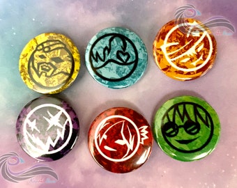 May include: Six round buttons with different designs. Each button has a different color background and a black and white design. The designs include a face with glasses, a face with a frown, a heart with waves, a face with a crown, a face with a frown, and a face with a crown.
