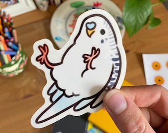 Puede incluir: Una pegatina de dibujos animados blanca y azul de un periquito con una cola azul claro y patas rosas. El pájaro está sentado de espaldas con las alas extendidas.