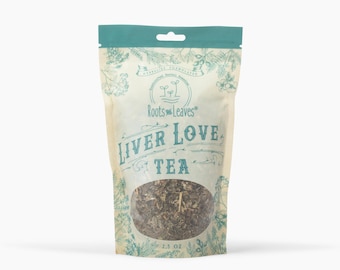 May include: A package of "Roots & Leaves" Liver Love Tea. The bag is beige with a teal top and a clear window showing the tea leaves. The text "Liver Love Tea" is in teal script. The bag contains 2.5 oz of tea.