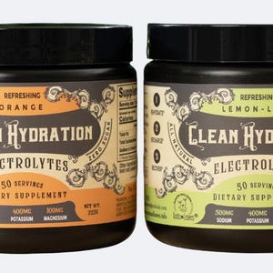 Puede incluir: Dos frascos negros de Clean Hydration Electrolytes, uno naranja y otro verde. Las etiquetas dicen "Refreshing Orange" y "Refreshing Lemon-Lime". Cada frasco contiene 50 porciones de suplemento dietético.