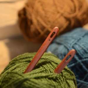 May include: Two wooden yarn needles with green, brown, and blue yarn balls.