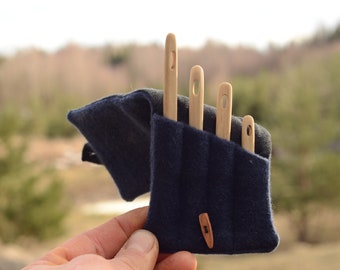 May include: A set of four wooden needles in a blue felt case with a wooden button closure. The needles are different sizes and are used for knitting or crocheting.