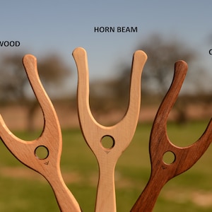 May include: Three wooden throwing sticks, each made from a different type of wood: beech, hornbeam, and oak. The sticks are all the same shape, with a U-shaped handle and a pointed end.
