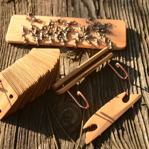 May include: A set of wooden tools for crafting, including a wooden board with metal hooks, a stack of wooden squares with holes, and a wooden tool with two loops.