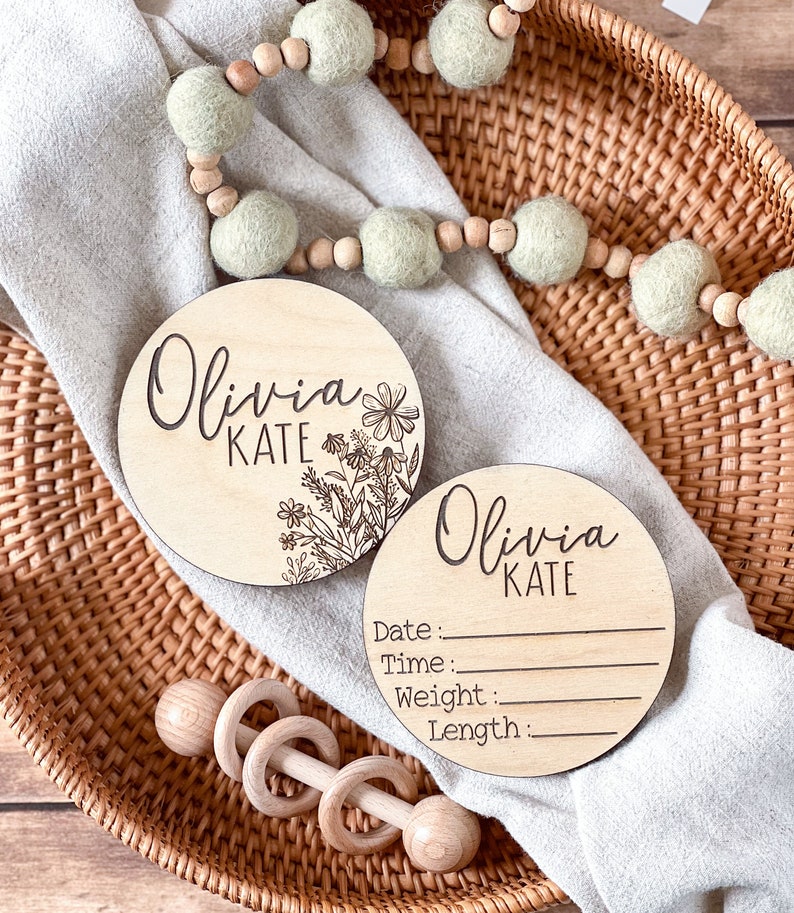 Engraved wood birth announcement discs for newborn photos, featuring floral details and space to write baby’s birth info.