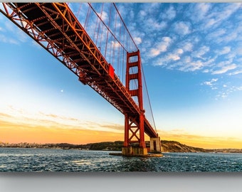 May include: A photograph of the Golden Gate Bridge in San Francisco, California. The bridge is red and spans a body of water. The sky is blue with white clouds.