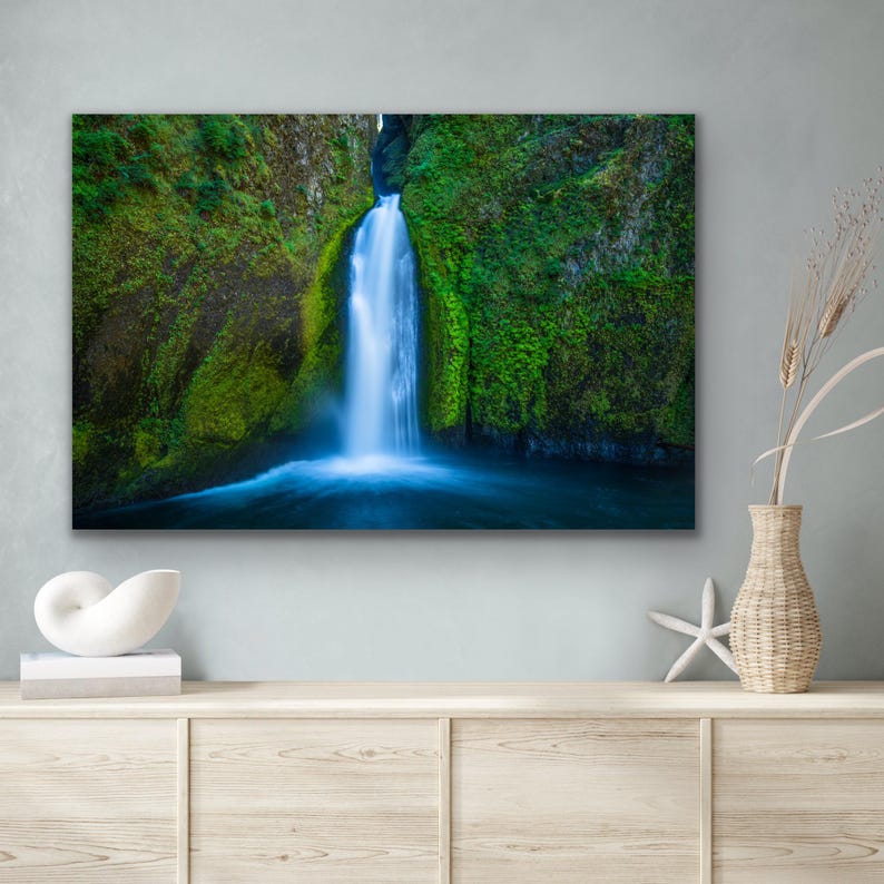 K&ouml;nnte beinhalten: Ein Foto eines Wasserfalls, der eine mit Moos bedeckte Felswand hinunterst&uuml;rzt. Das Wasser ist leuchtend blau und das Moos ist ein sattes Gr&uuml;n. Der Wasserfall ist von einem tiefblauen Wasserbecken umgeben.