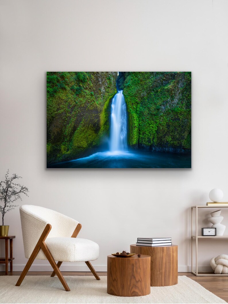 K&ouml;nnte beinhalten: Ein Foto eines Wasserfalls, der eine mit Moos bedeckte Felswand hinunterst&uuml;rzt. Das Wasser ist leuchtend blau und die umliegende Vegetation ist ein sattes Gr&uuml;n.