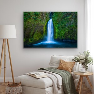 K&ouml;nnte beinhalten: Ein Wasserfall st&uuml;rzt &uuml;ber eine mit Moos bedeckte Felswand und bildet am Fu&szlig;e einen leuchtend blauen Teich. Das &uuml;ppige Gr&uuml;n der umliegenden Vegetation verst&auml;rkt die nat&uuml;rliche Sch&ouml;nheit der Szene.