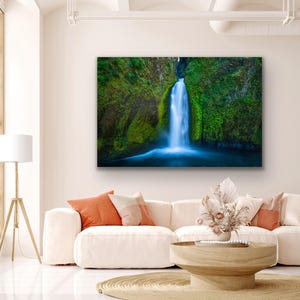 K&ouml;nnte beinhalten: Ein Foto eines Wasserfalls, der eine mit Moos bedeckte Felswand hinunterst&uuml;rzt. Das Wasser ist leuchtend blau und die umliegende Vegetation ist ein sattes Gr&uuml;n.