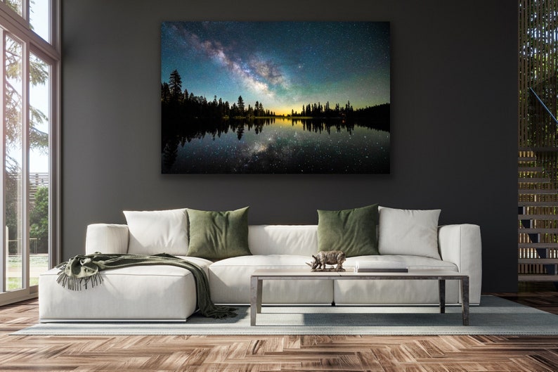 May include: A photograph of a lake reflecting the Milky Way at night. The lake is surrounded by trees and the sky is filled with stars.