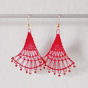 May include: A pair of red crocheted earrings with gold hooks and red beads hanging from the bottom.