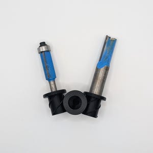 May include: Two woodworking router bits with blue painted sections and black rubber collars. The bits are made of metal and are designed for shaping and cutting wood. The bits are set against a white background.