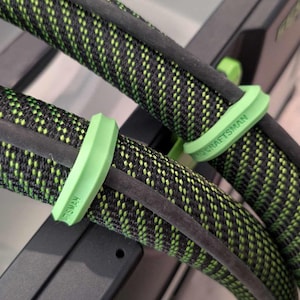 May include: Close-up of two black and green cables with green cable ties. The cable ties have the word "CRAFTSMAN" printed on them.