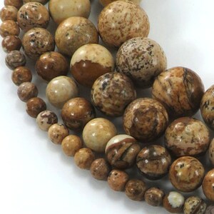May include: Strands of natural stone beads in varying sizes and shades of brown, tan, and cream. The beads have unique patterns and textures, creating a natural and earthy aesthetic. The beads are strung together, ready for jewelry making.