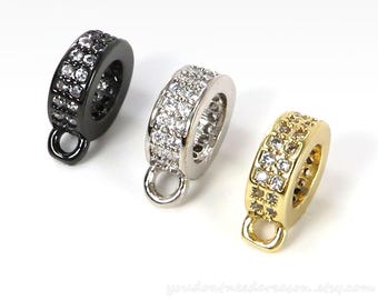 May include: Three pendant charms with a ring design. Each charm has a loop at the top for attaching to a necklace or bracelet. The charms are available in black, silver, and gold finishes. Each charm is adorned with a double row of clear cubic zirconia stones.