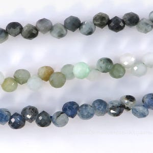 May include: Three strands of faceted gemstone beads in shades of green, blue, and white. The beads are round with multiple facets, creating a sparkling effect. The beads are strung together, ready for jewelry making.