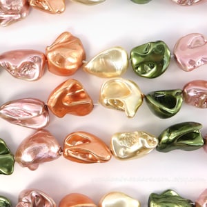 May include: Strands of iridescent beads in various colors, including pink, orange, gold, and green. The beads have an irregular, organic shape and are strung together with a thin, white thread. The beads are likely used for jewelry making.