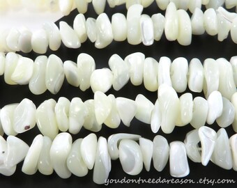 May include: A strand of irregular, tumbled white mother-of-pearl shell beads with a smooth, lustrous finish. The beads are strung together in a multi-row arrangement, displaying natural variations in shape and size. Text reads youdontneedareason.etsy.com.