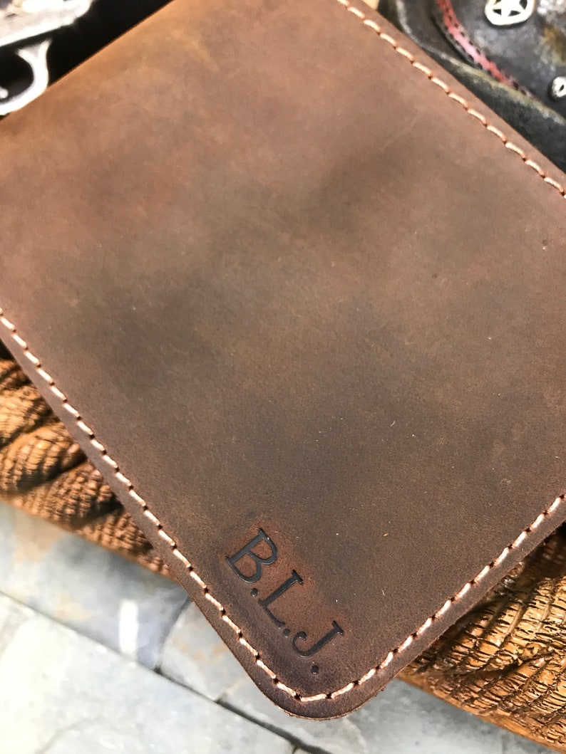 May include: A brown leather wallet with a stitched edge and the initials "B.L.J." embossed on the front.