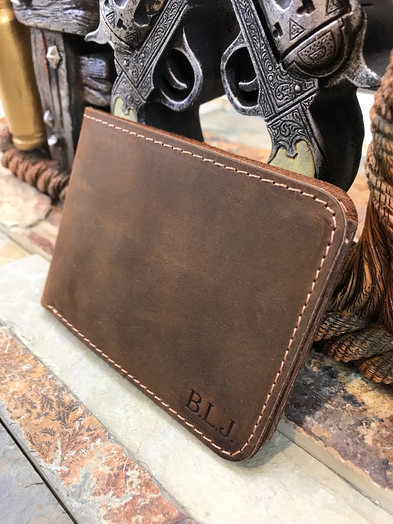 May include: A brown leather wallet with a stitched edge and the initials "B.L.J." embossed on the front.
