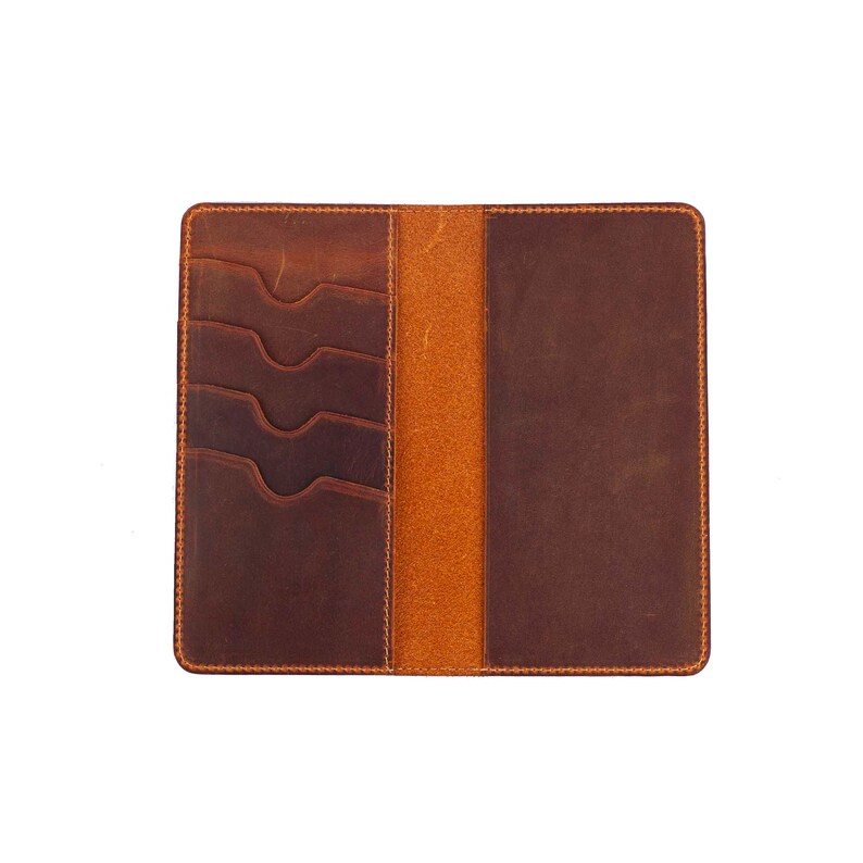 Puede incluir: Una cartera de cuero marr&oacute;n con m&uacute;ltiples ranuras para tarjetas y un portafolios. La cartera est&aacute; abierta para mostrar el interior.