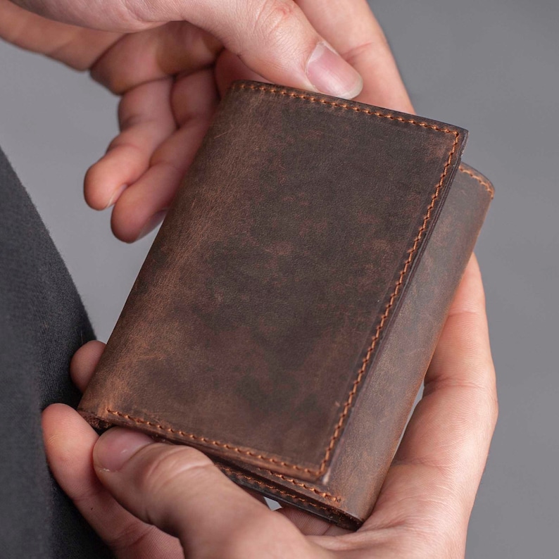 May include: A brown leather wallet with a distressed finish and stitched edges.