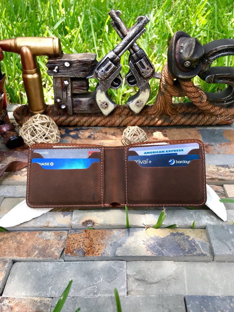 May include: An open brown leather wallet with a stitched edge, displaying two credit cards. The cards are a Chase credit card and an American Express credit card with the Barclaycard logo. The wallet is resting on a stone surface.
