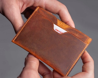 May include: A brown leather wallet with a stitched edge and a single card slot that says "DRIVER" in red.